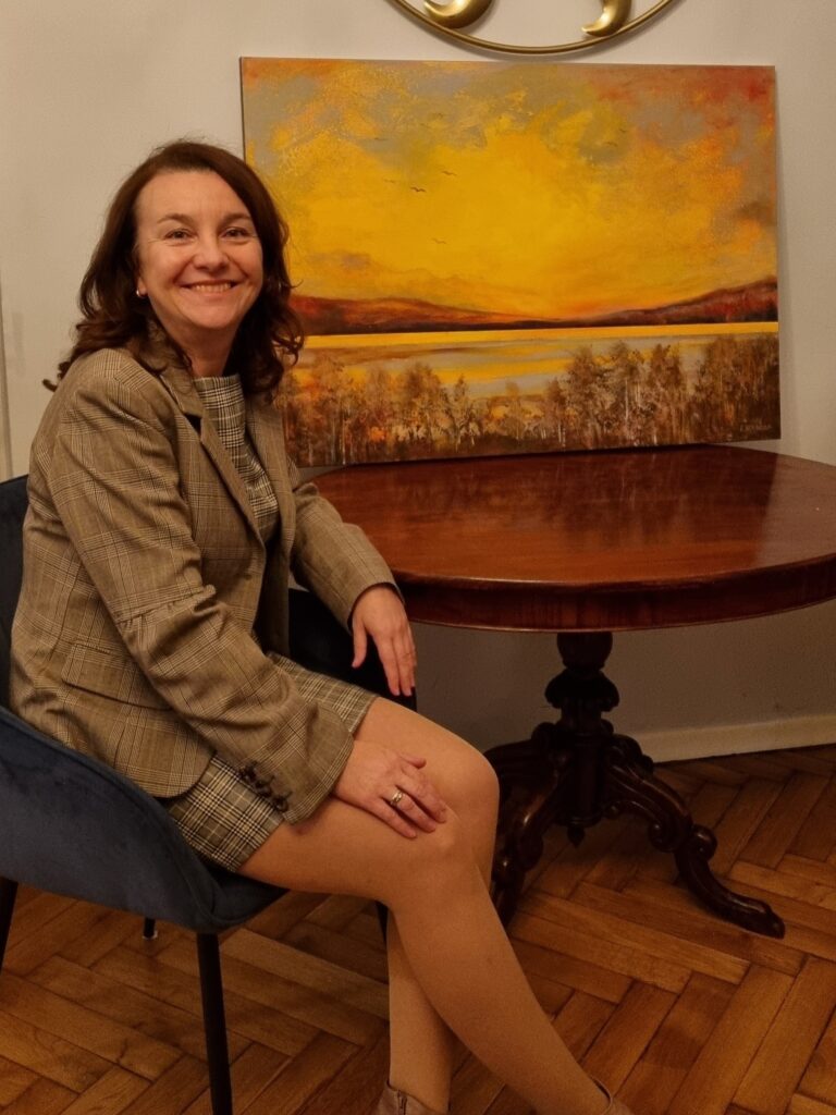 Photo of the artist, Ewa Konarska in front of one of her paintings.